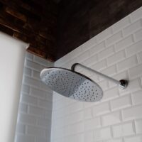stainless steel shower head on white brick wall