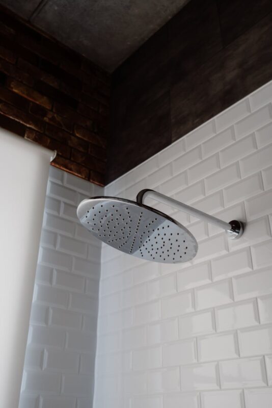 stainless steel shower head on white brick wall
